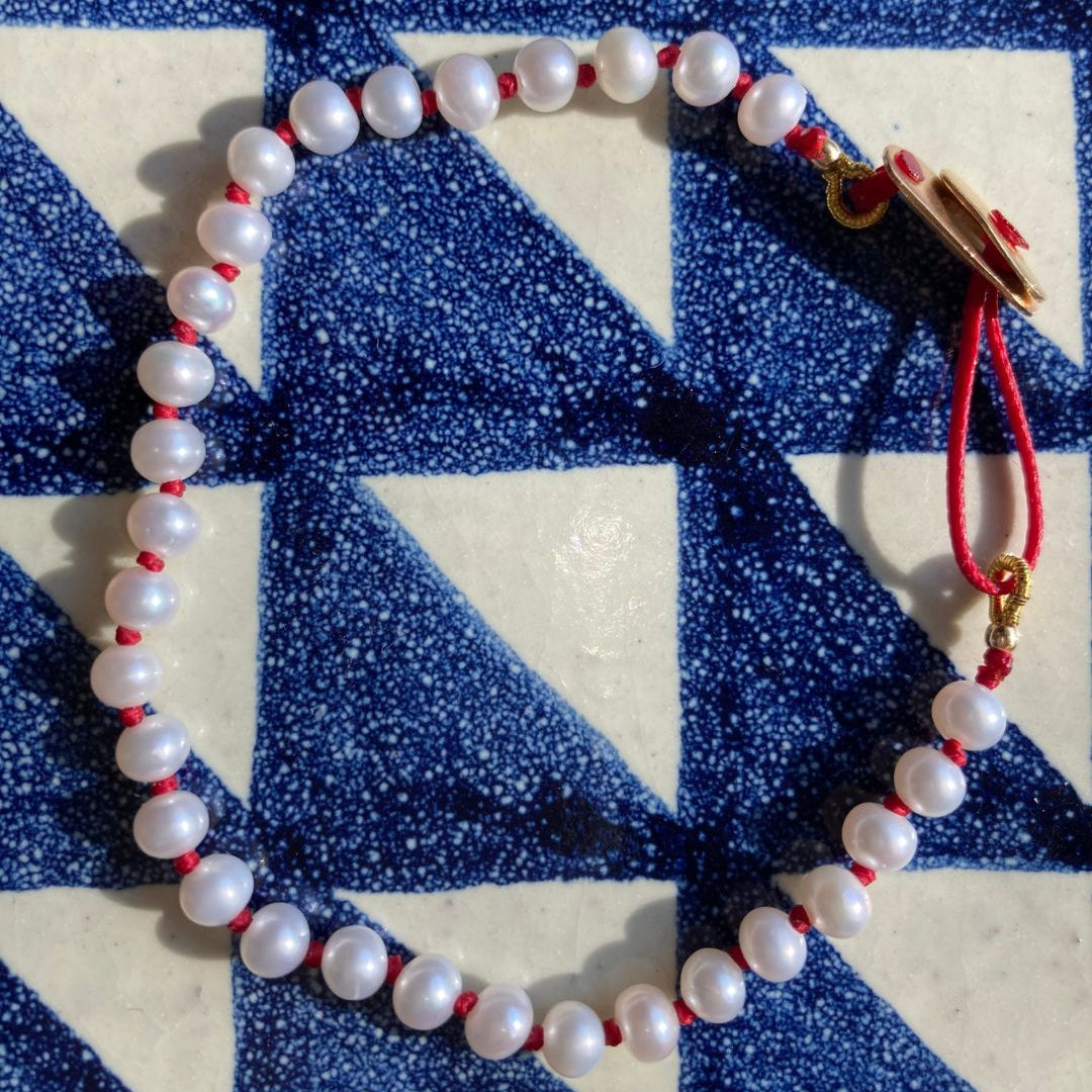 KImolos-bracelet_artisanal_Mymosaa_en_perles_et_cordon_rouge_or__argent_sur_fond_carrelage_carre