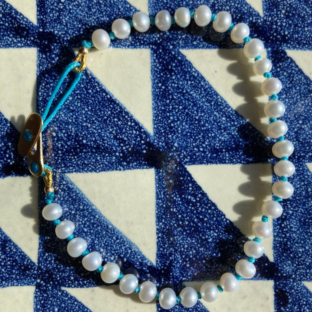 KImolos-bracelet_artisanal_Mymosaa_en_perles_et_cordon_turquoise_or__argent_sur_fond_carrelage_carre