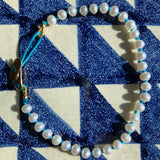 KImolos-bracelet_artisanal_Mymosaa_en_perles_et_cordon_turquoise_or__argent_sur_fond_carrelage_carre