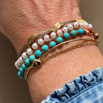 KImolos-bracelet_artisanal_Mymosaa_en_perles_etcordon_rouge_or__argent_porte_avec_bracelets_sur_fond_neutre