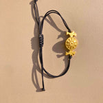 OFRYNIO_bracelets_avec_medaillon_en_argent_et_or_porte_bonheur_avec_cordon_ajustable_noir_sur_fond_neutre