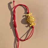 OFRYNIO_bracelets_avec_medaillon_en_argent_et_or_porte_bonheur_avec_cordon_ajustable_rouge_sur_fond_neutre