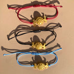 OFRYNIO_bracelets_avec_medaillon_en_argent_et_or_porte_bonheur_avec_cordon_ajustable_sur_fond_neutre